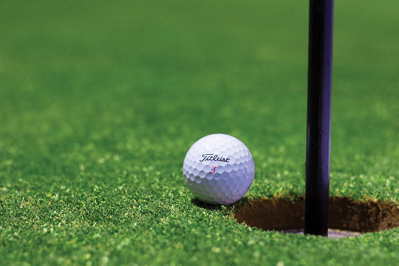 A golf ball on the verge of entering the hole